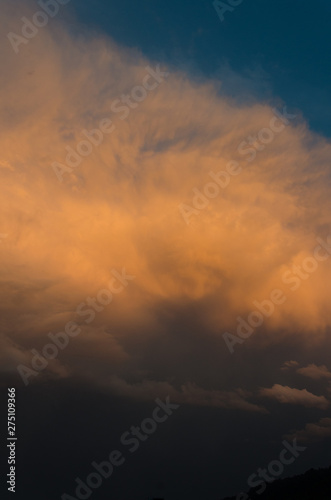 Dramatic clouds of thunderstorm in orange sunlight. Sunset on summer evening.