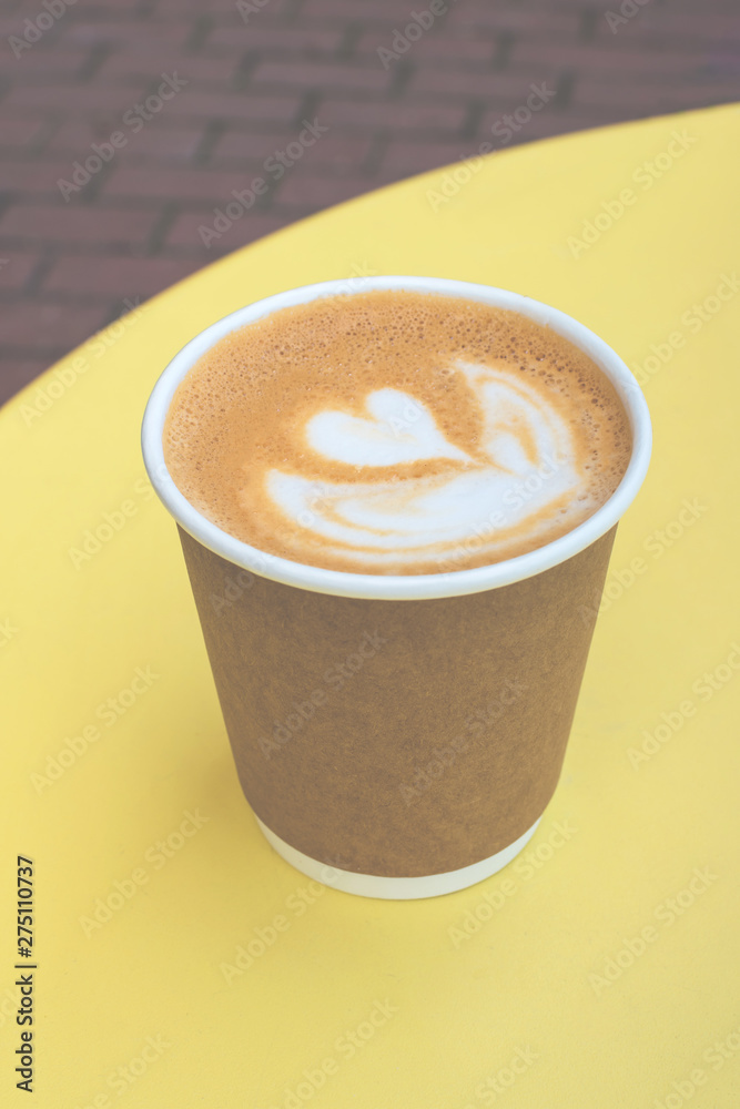 Paper cup of coffee take-away on yellow table with copy space. Paper cup of coffee take-away on yellow table with copy space.