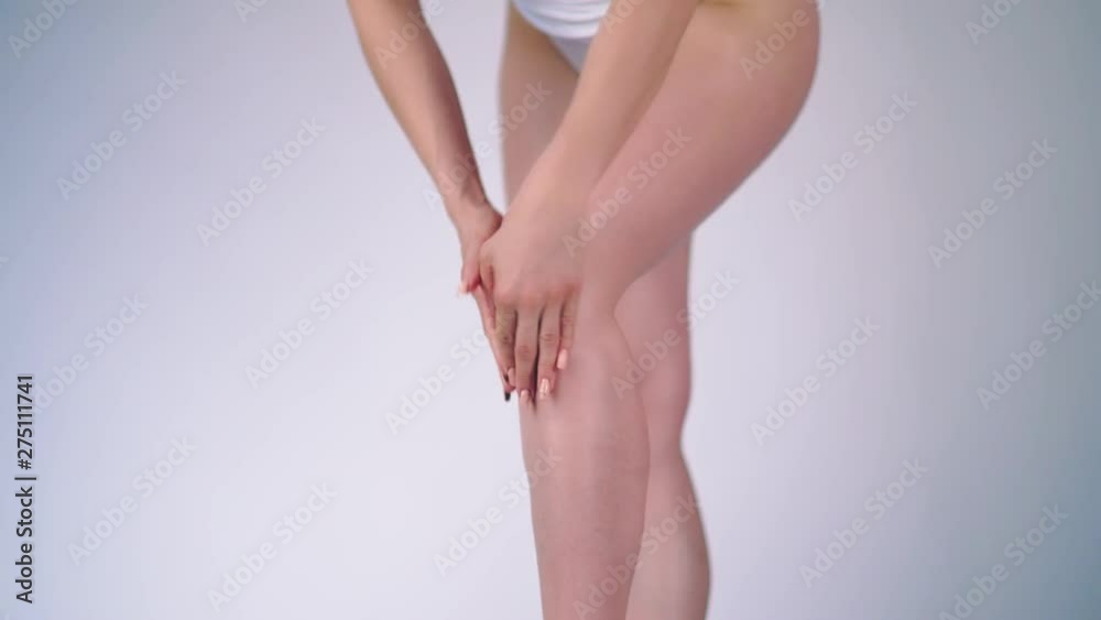 Woman applying moisturizer cream or body lotion on her legs on a white background. Concept of depilation, smooth skin, skincare and body Woman applying moisturizer cream or body lotion on her legs on a white background. Concept of depilation, smooth skin, skincare and body
