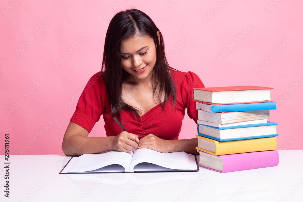 Young Asian woman read a book with books on table. Young Asian woman read a book with books on table.