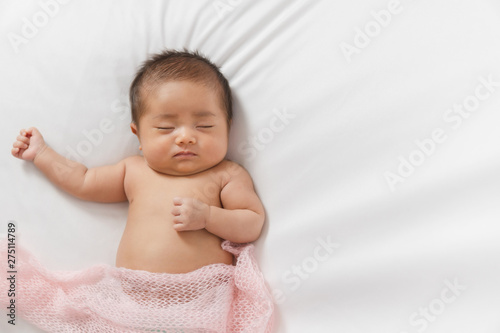 Adorable asian newborn baby in pink wrap sleeping on white blanket background.