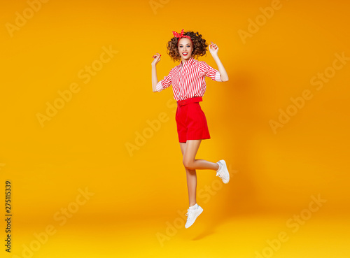 Fototapeta Naklejka Na Ścianę i Meble -  . concept happy emotional young woman in red  jumping   on yellow background