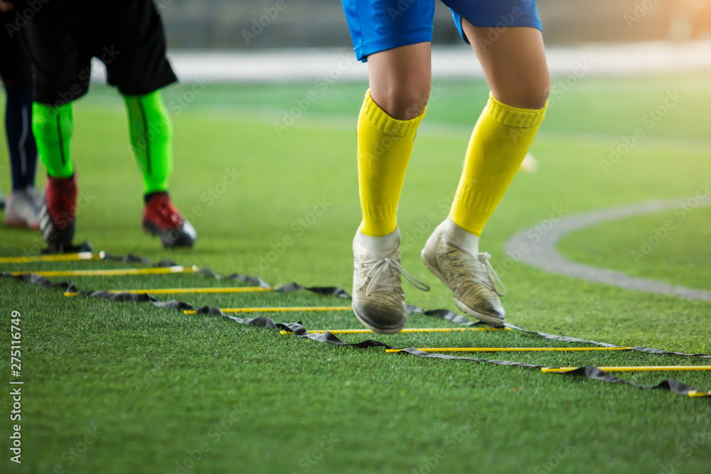 blurry soccer player is jumping between marker for football training with other players waiting to follow him. ladder drills exercises for football team. blurry soccer player is jumping between marker for football training with other players waiting to follow him. ladder drills exercises for football team.