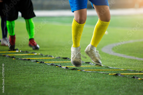 blurry soccer player is jumping between marker for football training with other players waiting to follow him. ladder drills exercises for football team.