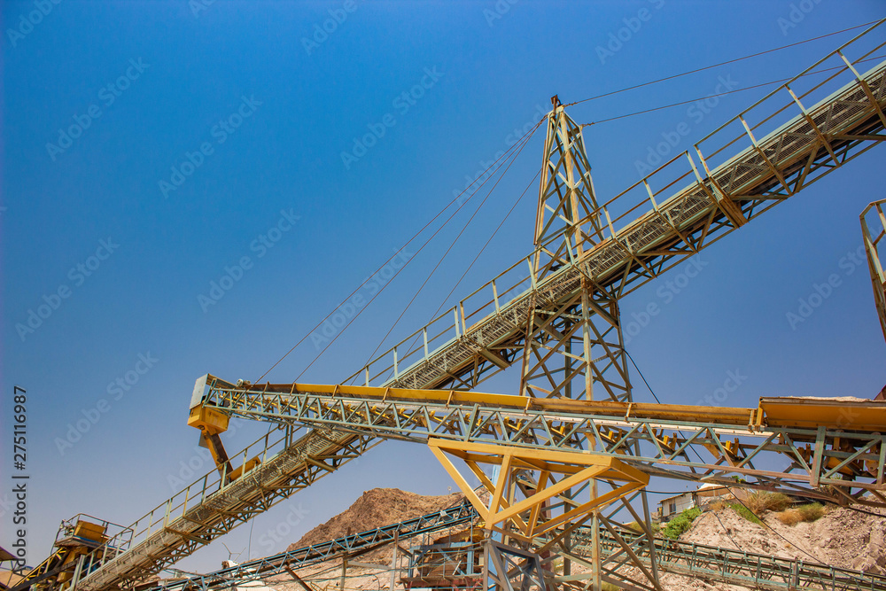 industrial cranes for building iron machines foreshortening from below on blue sky background, copy space 