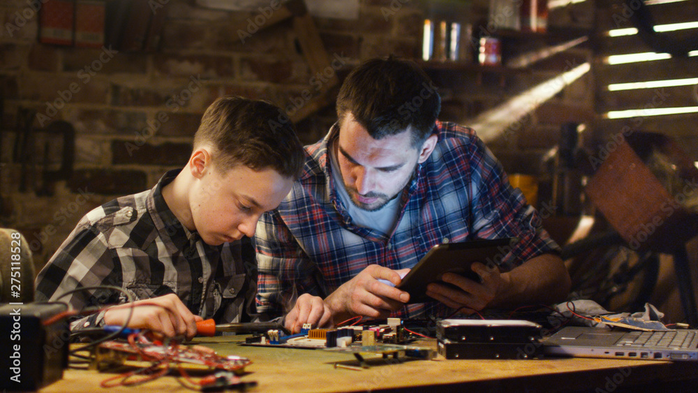 Fototapeta premium Father and son are soldering a circuit board in a garage at home.