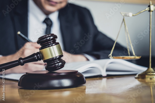 Professional Male lawyer or judge working with contract papers, documents and gavel and Scales of justice on table in courtroom, Law and Legal services concept