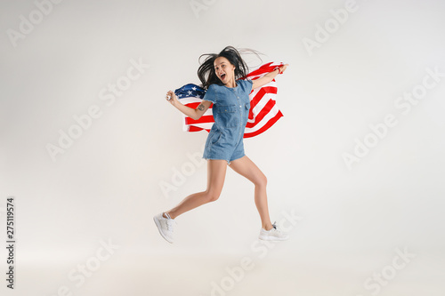 Celebrating an Independence day. Stars and Stripes. Young woman with the flag of the United States of America isolated on white studio background. Looks crazy happy and proud as a patriot of her