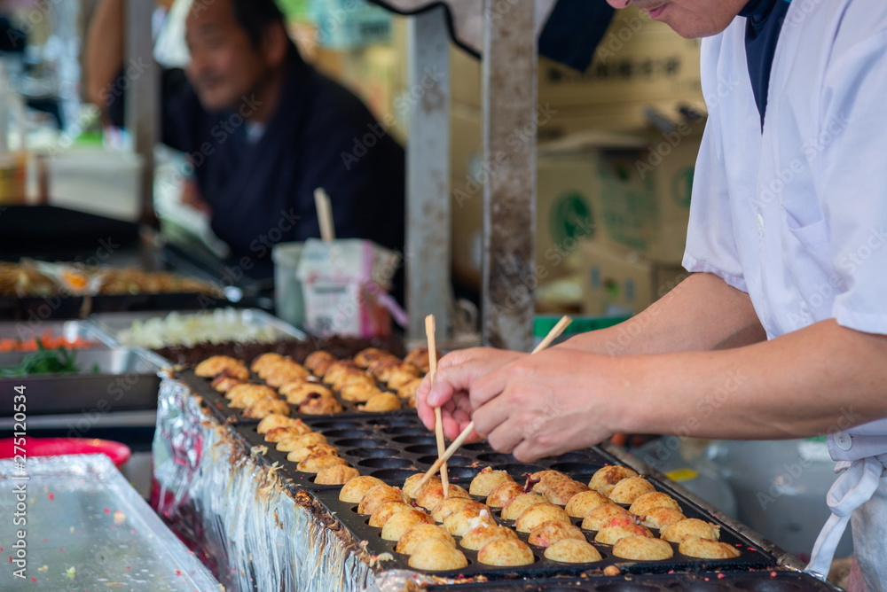 Moving hand of street food chef making takoyaki traditional Japanese