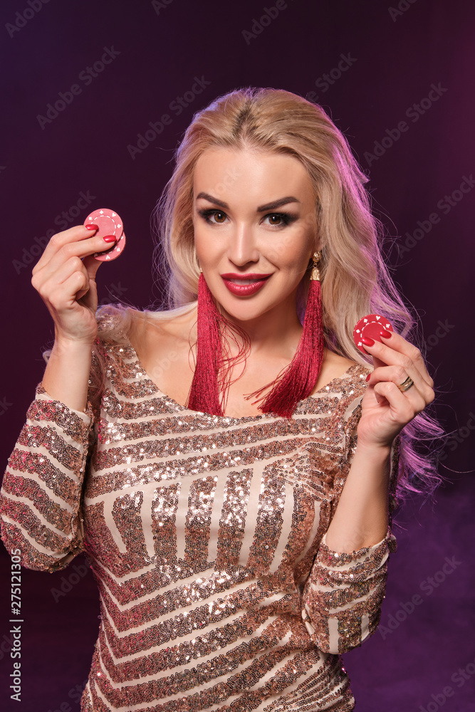 Blonde woman with a perfect hairstyle and bright make-up is posing with gambling chips in her hands. Casino, poker. Blonde woman with a perfect hairstyle and bright make-up is posing with gambling chips in her hands. Casino, poker.