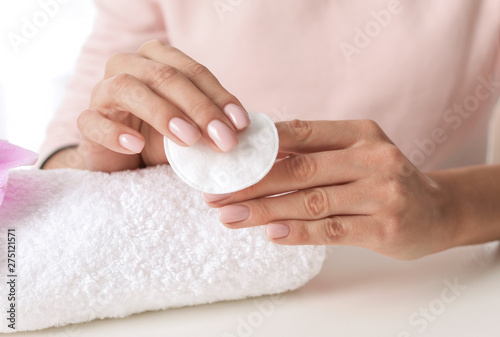 Woman removing polish from nails with cotton pad at table  closeup