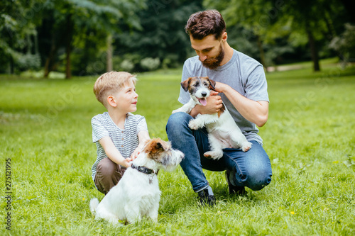 Canvas Print Hipster beard dad and child playing with two dogs Jack Russel terrier on nature