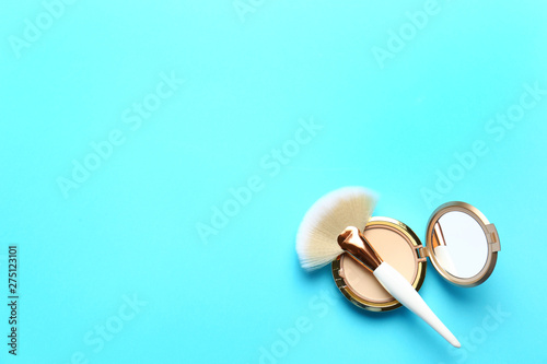 Professional makeup brush and face powder on light blue background, top view. Space for text