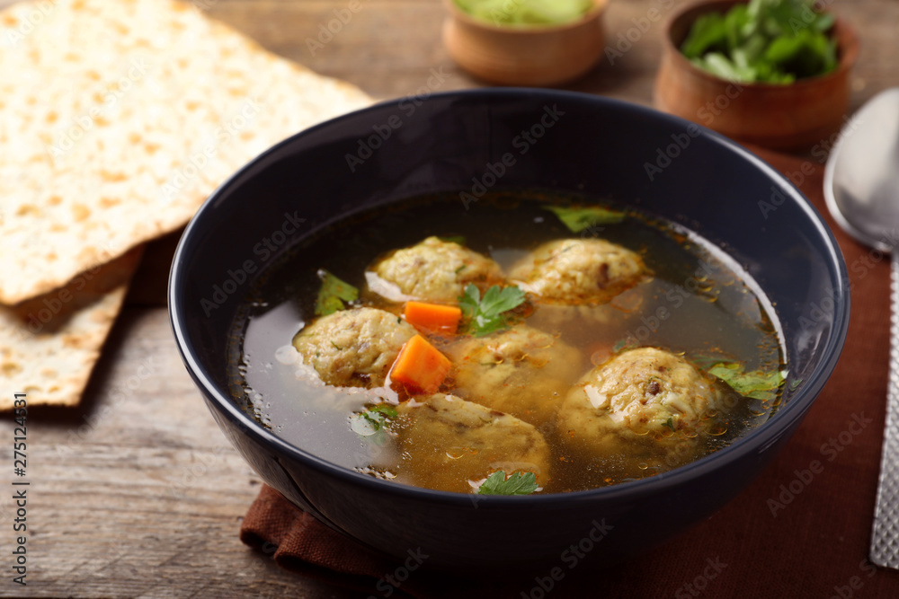 Bowl of Jewish matzoh balls soup on wooden table