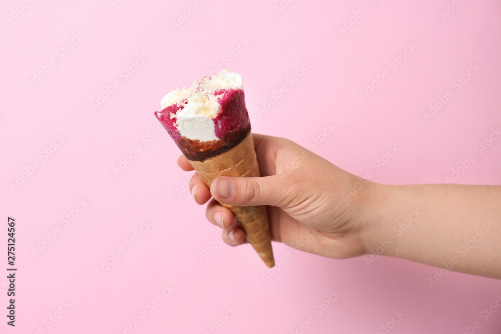 Woman holding waffle cone with delicious ice cream on color background Woman holding waffle cone with delicious ice cream on color background