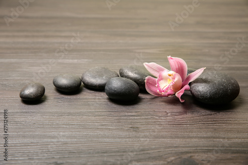Spa stones with orchid flower on wooden background