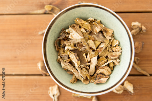 culinary, food and cooking concept - dried mushrooms in bowl on wooden background