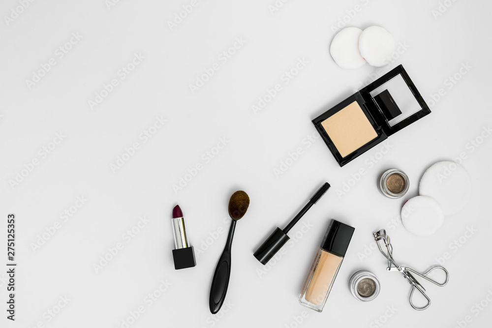 Obraz premium Cosmetic sponges; compact powder; foundation; lipstick eyeshadow; eyelash curler and brushes on white background