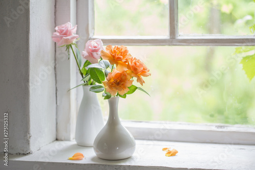 beautiful roses in vases on old wooden windowsill