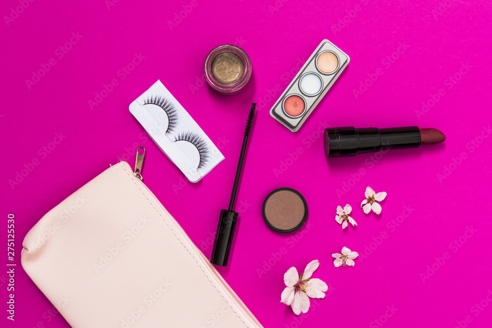 Spring blossom; eyelashes; eyeshadow; lipstick; mascara brush and blossom with pink makeup bag on pink background Spring blossom; eyelashes; eyeshadow; lipstick; mascara brush and blossom with pink makeup bag on pink background
