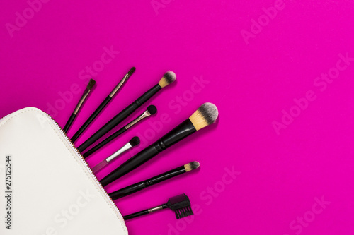 Fototapeta Naklejka Na Ścianę i Meble -  Many makeup brushes out of white bag over the pink backdrop