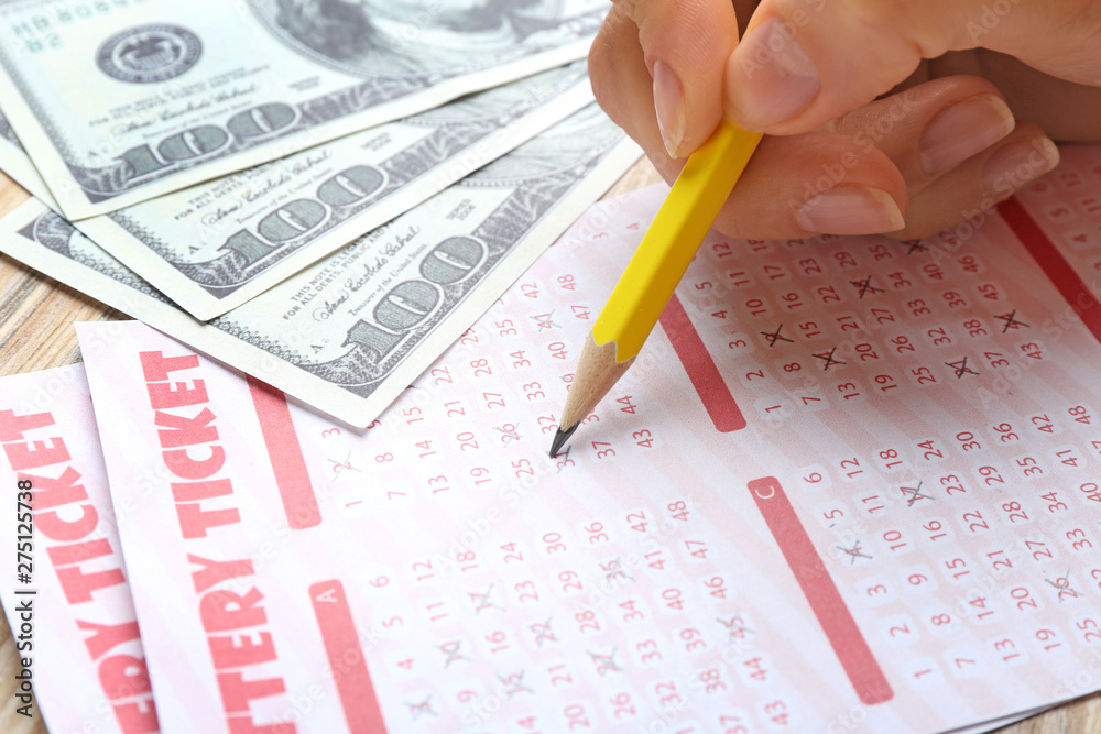 Woman filling out lottery tickets with pencil and money on wooden table, closeup. Space for text Woman filling out lottery tickets with pencil and money on wooden table, closeup. Space for text