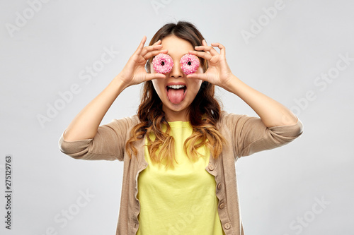 people, fast food and fun concept - happy asian young woman with donuts instead of eyes making faces over grey background