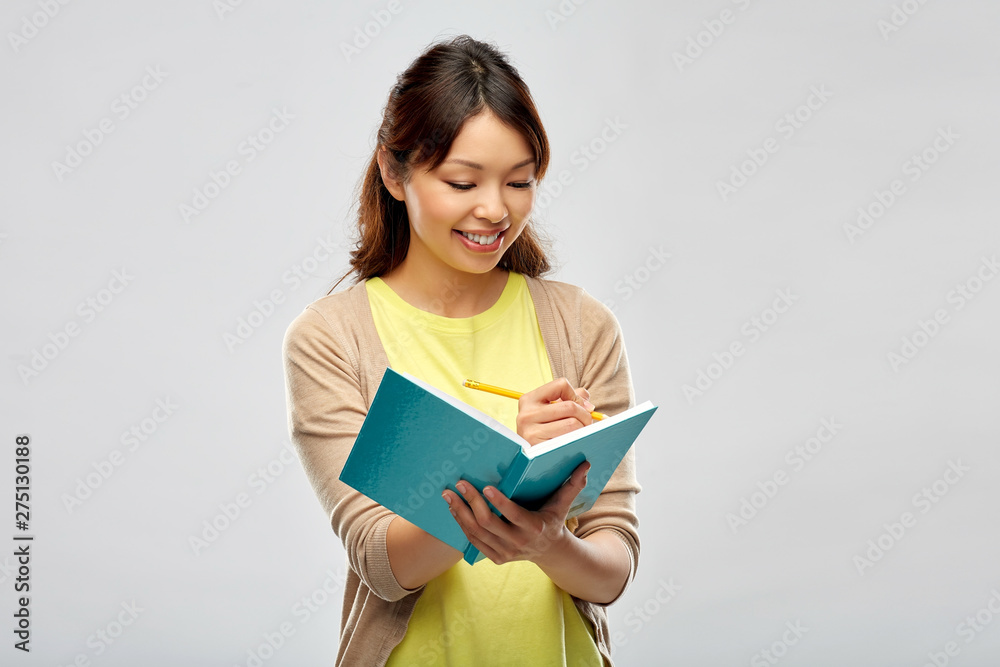 education, school and inspiration concept - smiling asian student or creative woman with diary and pencil over grey background education, school and inspiration concept - smiling asian student or creative woman with diary and pencil over grey background