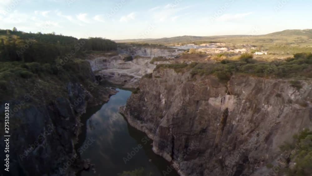 Fly over reveals a quarry and swiftly flowing river cutting the land in two Fly over reveals a quarry and swiftly flowing river cutting the land in two