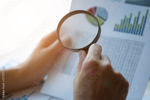 Man looking through a magnifying glass to documents. Business assessment and audit. Magnifying glass on a financial report. Close-up Of person Checking Bills With Magnifying Glass.Concept of search