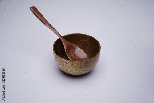 a wooden bowl and a wooden spoon or spatula on wooden background