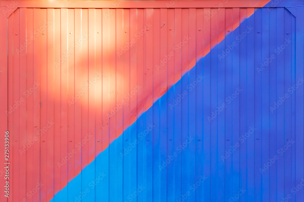 Background made of metal profile painted in blue and red on the fence or container backlit by the sun Background made of metal profile painted in blue and red on the fence or container backlit by the sun