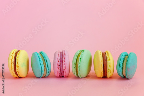 Sweet almond colorful unicorn pink blue yellow green macaron or macaroon dessert cake isolated on trendy pink pastel background. French sweet cookie. Minimal food bakery concept. Copy space