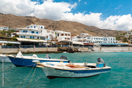 Small moored fishing boats in blue lagoon of Crete island.