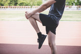 Young fitness athlete man running on road track, exercise workout wellness and runner stretching legs before run concept