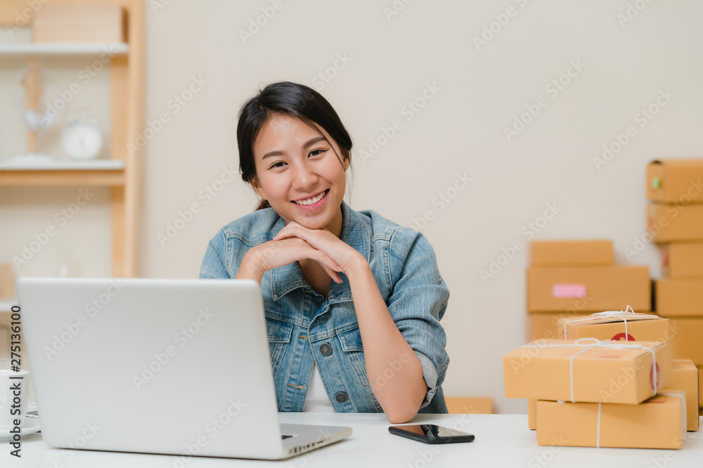 Business woman feeling happy smiling and looking to camera while working in her office at home. Beautiful Asian young entrepreneur owner of SME with small business owner at home office concept. Business woman feeling happy smiling and looking to camera while working in her office at home. Beautiful Asian young entrepreneur owner of SME with small business owner at home office concept.