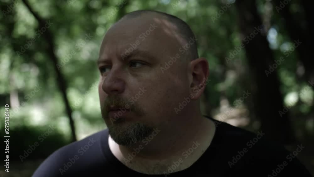 A man walking through forest trees. Tree shadows fall on him and sunlight shines through. Slowmotion clip. A man walking through forest trees. Tree shadows fall on him and sunlight shines through. Slowmotion clip.