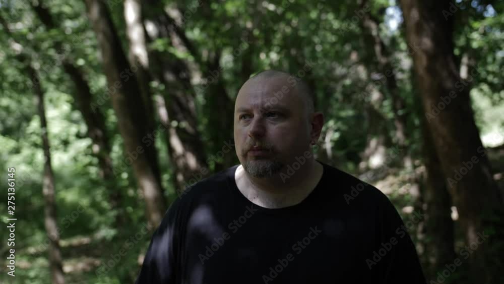 A man walking through forest trees. Tree shadows fall on him and sunlight shines through. Slowmotion clip. A man walking through forest trees. Tree shadows fall on him and sunlight shines through. Slowmotion clip.