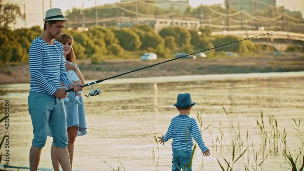 Family on fishing - father fishing - his wife holding a baby - little boy walking on the beach Family on fishing - father fishing - his wife holding a baby - little boy walking on the beach