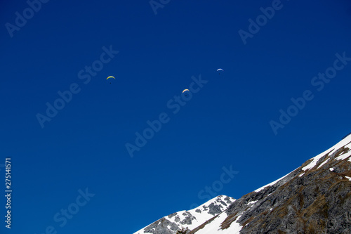 View of three paragliders in the swiss alps
