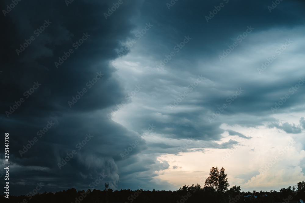 Dramatic cloudscape. Sunny light through dark heavy thunderstorm clouds before rain. Overcast rainy bad weather. Storm warning. Natural blue background of cumulonimbus. Sunlight in stormy cloudy sky.