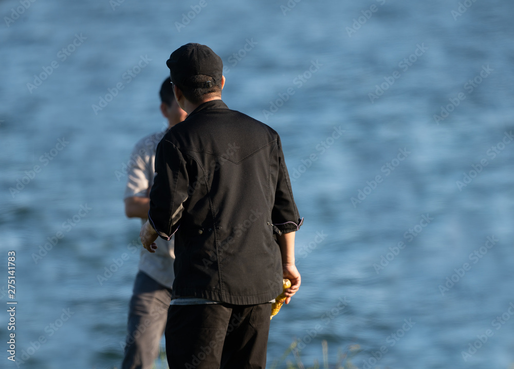 unknown fisherman is having a conversation with an associate while holding corn at a cookout on a sunny day at the park unknown fisherman is having a conversation with an associate while holding corn at a cookout on a sunny day at the park