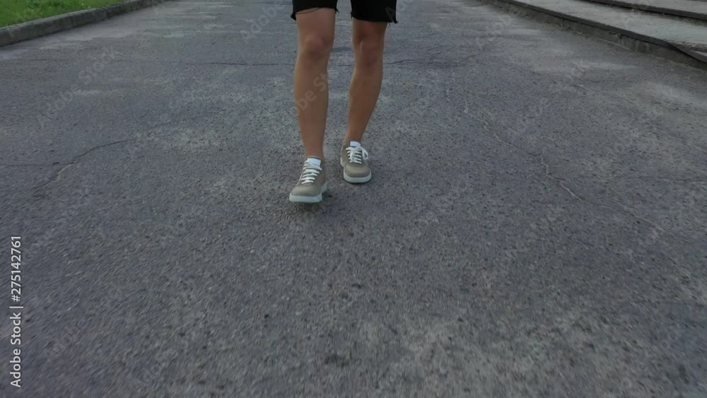 A man walks on the asphalt in brown sneakers. Front view. Close-up. A man walks on the asphalt in brown sneakers. Front view. Close-up.