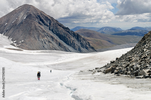 Western Mongolia mountainous landscape. Two climbers climb Potanin Glacier and Khuiten Peak (4374 m, the highest summit in Mongolia). Altai Tavan Bogd National Park, Bayan-Ulgii Province, Mongolia.