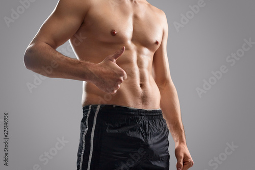 Crop shirtless bodybuilder showing thumb up