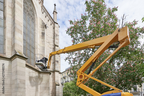 Special machine for lifting to a height. A worker makes restoration of an old building of the Evangelical Church at a high altitude, using a lifting machine.