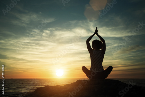 Meditation girl on the sea during sunset. Yoga silhouette.