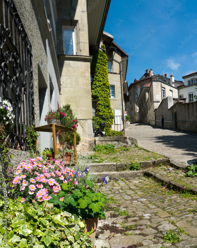 Fototapeta premium histoirc cobblestone streets and buildings in the old town of the Swiss city of Fribourg with tourist walking around