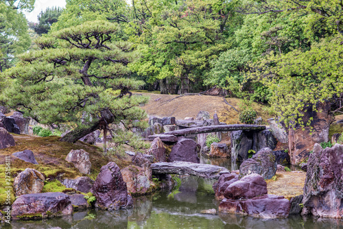 Beautiful scenery at Nijo Castle. View of the formal gardens, with a pond and stone bridges. On a rainy day, droplets are visible in the air.