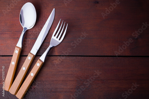 Rustic set of cutlery knife, spoon, fork. Dining set with wooden handles. Wooden background. Copy space. Top view